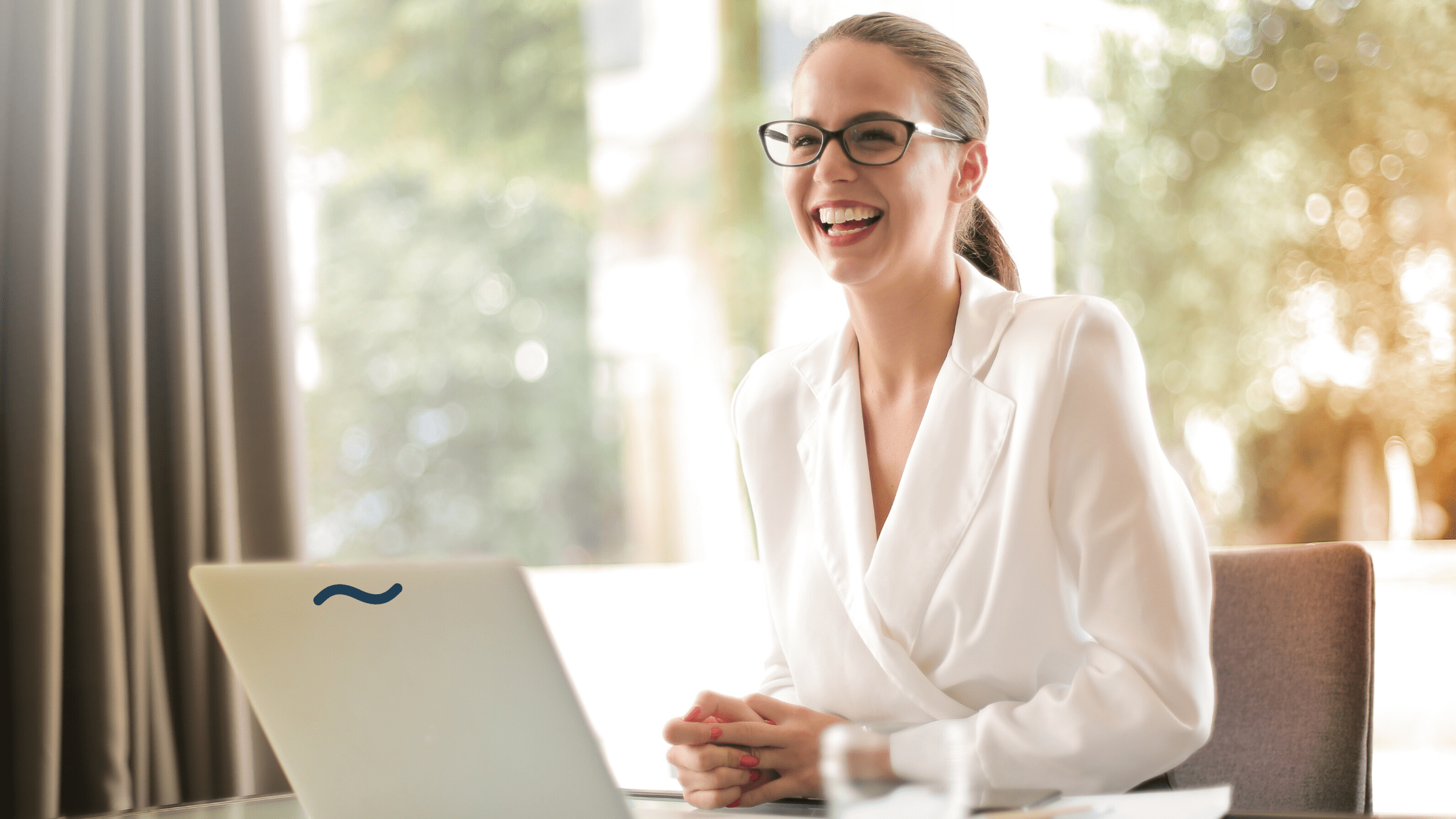 Profissional de Inside Sales sorrindo em frente ao computador.