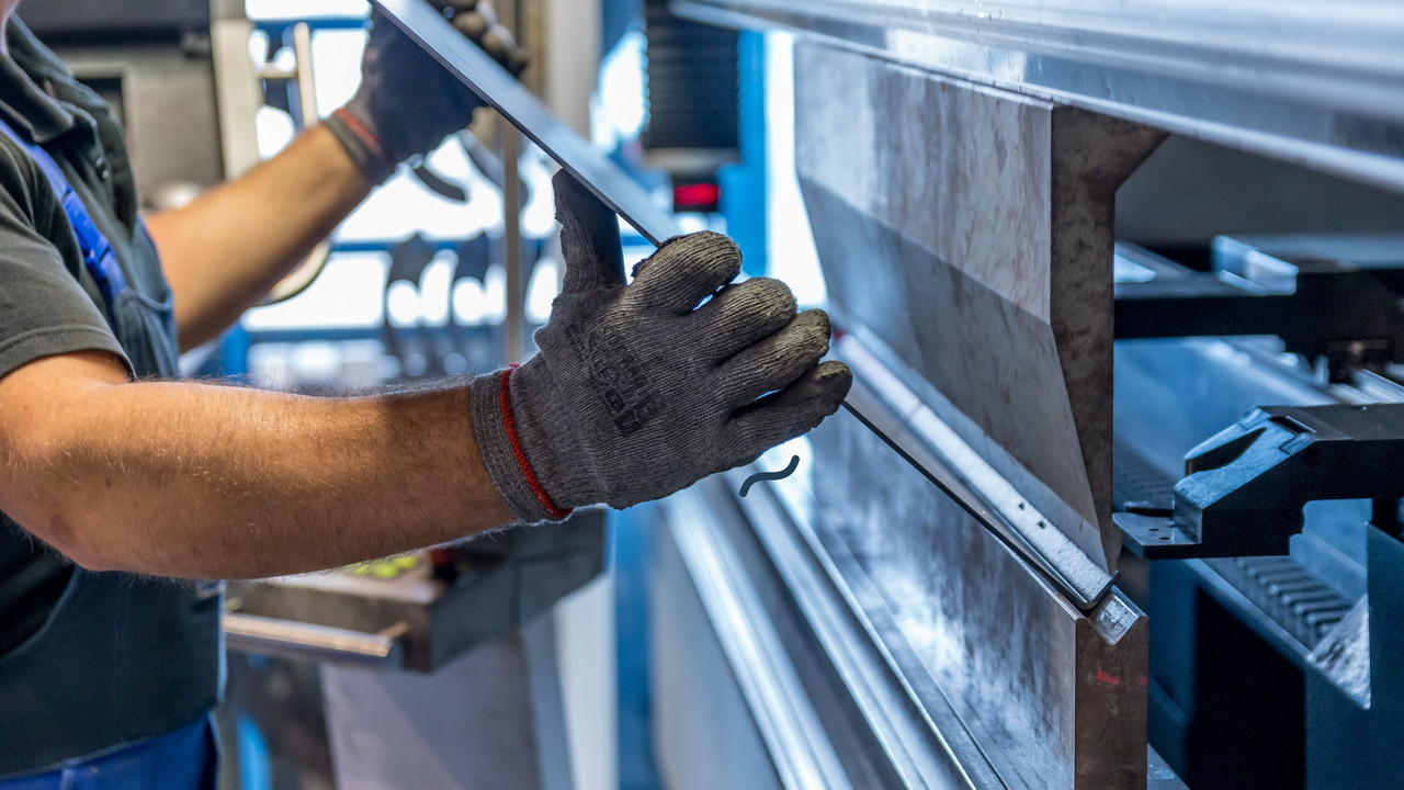 Profissional trabalhando com máquina em indústria. Imagem simboliza a verificação do indicador OEE.