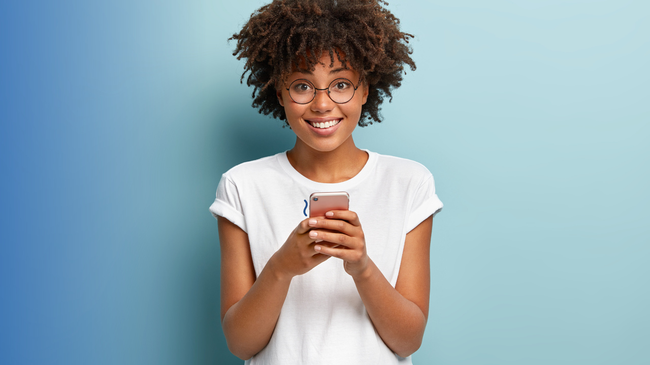 Menina sorrindo com celular na mão. Imagem representa o Customer Experience (experiência do cliente).