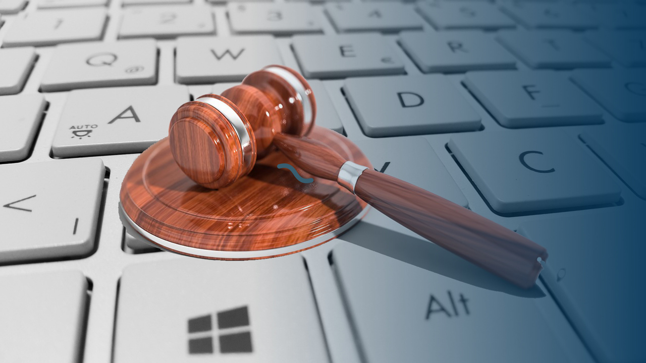 Martelo de juiz em cima de teclado. Imagem representa os benefícios em usar o ERP no Compliance Fiscal.